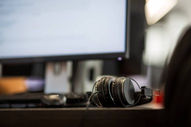 Çalışma alanındaki ofis monitörünün yanındaki masada kulaklıklar.