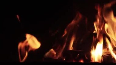 Şöminede yangın, yavaş çekim video odunları ateş ve alevlerle yanıyor. Karanlıkta fotokopi aletiyle parlayan ateş. Yanal kamera hareketi.
