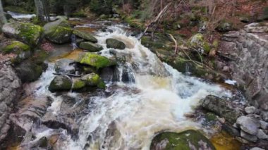 Bir dağ ormanında akan bir nehirdeki şelale vadideki kayaların arasında, kaynayan ve köpüren suyun hızlı akışı, yavaş çekimde su fışkırıyor.