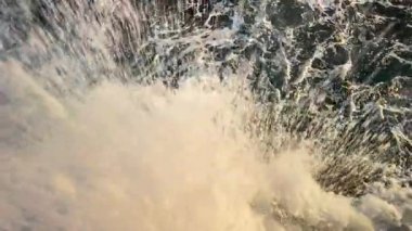 Köpüklü deniz dalgaları kayalık kıyılara çarpıyor.