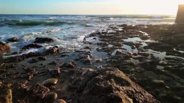 Köpüklü deniz dalgaları kayalık kıyılara çarpıyor.