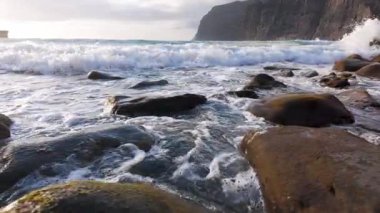 Los Gigantes, Tenerife, Kanarya Adaları, İspanya 'nın kayalık sahillerinde köpüklü deniz dalgalarının panoramik görüntüsü. Yavaş çekim klibi.