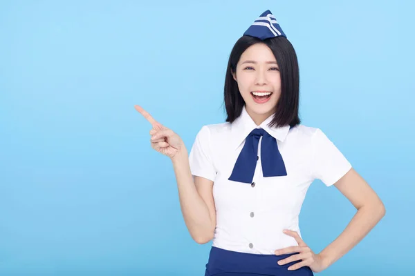 Happy Beautiful Airline Stewardess Wijzend Naar Iets Blauwe Achtergrond — Stockfoto