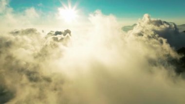 Güneşin doğuşunda bulutların olduğu sisli sabah dağlarının hava manzarası. 