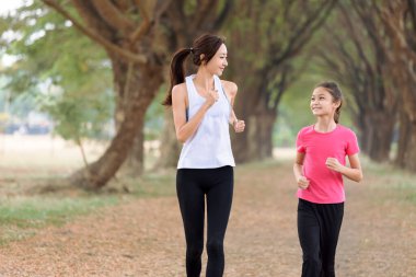 Anne ve kızı parkta koşuyor.