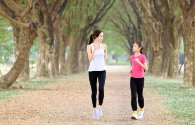 Mutlu anne ve kız parkta koşuyor.
