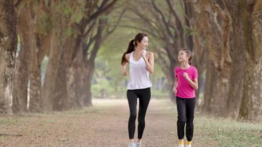 Mutlu anne ve kız parkta koşuyor.