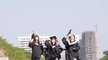 Happy students running and throwing graduation hats in air