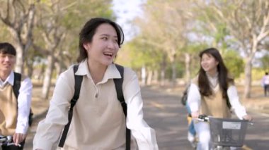 Happy teenager students riding bicycle at the school