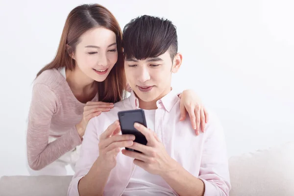 幸せな若いアジアのカップルは 携帯電話を使用して インターネットを閲覧し オンラインでチャット 自宅でソファでリラックス — ストック写真