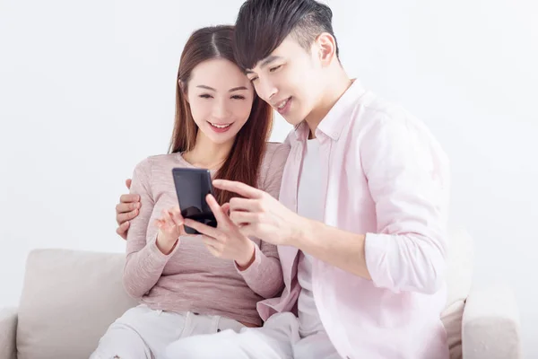 若いカップルは スマートフォンを使用して インターネットを閲覧し オンラインでチャット 自宅でソファでリラックス — ストック写真