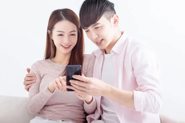 若いカップルは スマートフォンを使用して インターネットを閲覧し オンラインでチャット 自宅でソファでリラックス — ストック写真