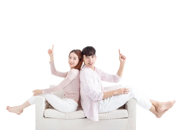 Glückliches Junges Paar Sitzt Auf Sofa Und Zeigt Mit Der — Stockfoto