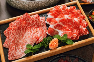 Daire şeklinde ahşap tabakta yüksek mermer dokuma dilimlenmiş domuz eti, sıcak kaplar ve Shabu için servis edilir..