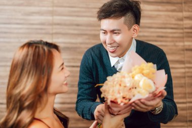 Genç adam sevgililer gününde restoranda kız arkadaşını selamlıyor.