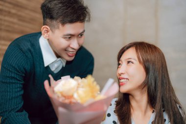 Genç adam sevgililer gününde restoranda kız arkadaşını selamlıyor.