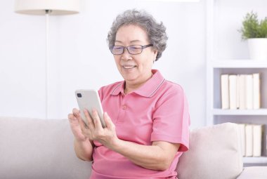 Kanepede oturan ve cep telefonunu karıştıran son sınıf öğrencisi kadın.