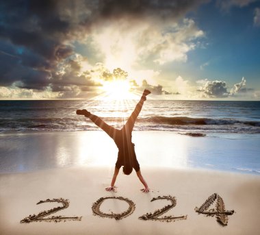 Sahilde heyecanlı genç adam amuda kalkıyor. Mutlu yıllar 2024.