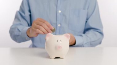 Para biriktirmek ve finansı planlamak için domuz kumbarasına para yatıran bir işadamı.