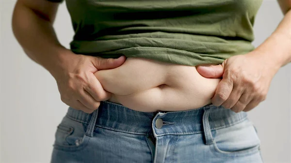 過度の腹脂肪をピンチする女性の手のクローズアップ ストック写真