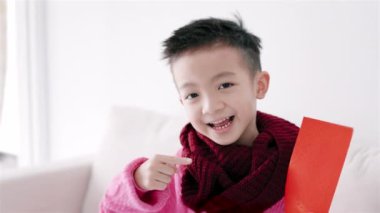 Kırmızı zarf tutan mutlu Asyalı çocuk. Mutlu Çin Yeni Yıl Konsepti.