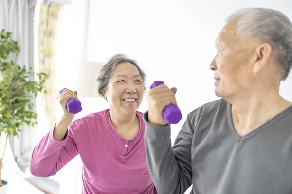 快乐的亚洲老年夫妇在室内用哑铃做运动 图库图片