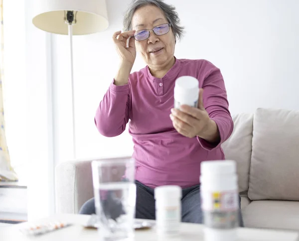 Старшая Женщина Читает Содержимое Коробке Лекарствами Дома Стоковое Изображение