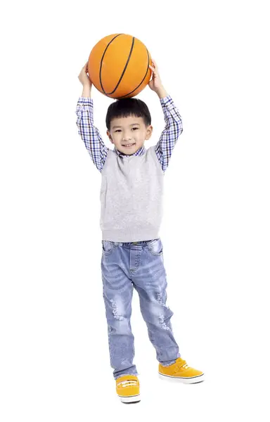 幸せなアジアの少年は 白い背景に隔離されたバスケットボールと微笑みを持っています ストック画像