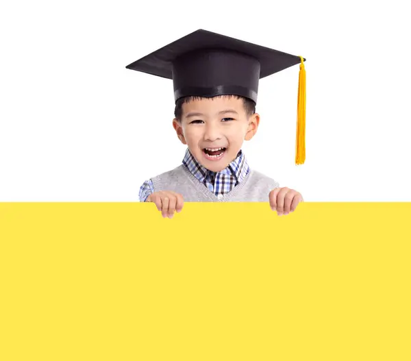 戴著毕业帽拿着黄色空横幅的快乐男孩 免版税图库照片