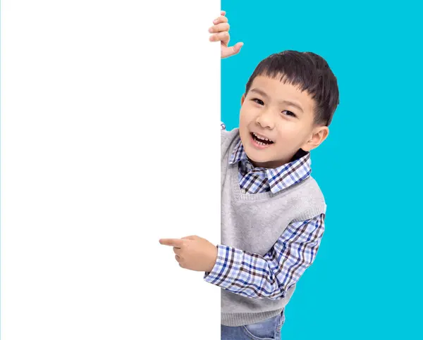 快乐的亚洲男孩举着并指着白色的空横幅 图库照片