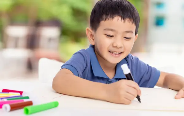 Lachende Aziatische Kind Schooljongen Studeren Schrijven Thuis Rechtenvrije Stockfoto's