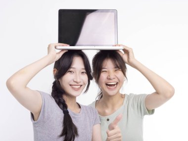 İki güzel, gülümseyen Asyalı genç bayan dizüstü bilgisayarı tutuyor.