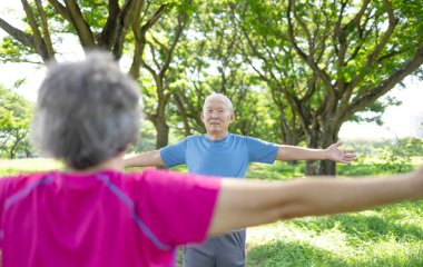 Mutlu Asyalı kıdemli çift meditasyon sırasında parkta temiz hava soluyor.