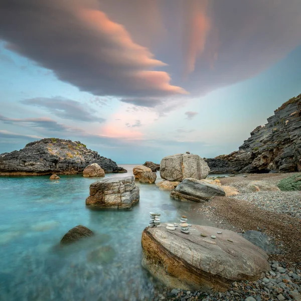 風景画 海の海岸で夜の時間 大きな岩やカラフルな劇的な雲 自然の美しい風景 ロイヤリティフリーのストック写真