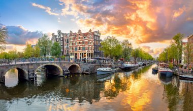 Amsterdam mı? Amsterdam şehir merkezinin panoramik manzarası. Amsterdam 'ın geleneksel evleri ve köprüleri. Renkli bir gün batımı zamanı. Tarihi bir şehre Avrupa seyahati. Avrupa, Hollanda, Hollanda, Amsterdam.