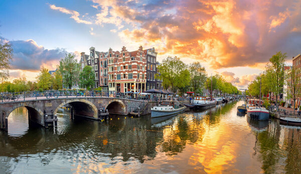 Amsterdam. Panoramic view of the downtown of Amsterdam. Traditional houses and bridges of Amsterdam. A colorful sundown time.   A European journey to a historic city. Europe, Netherlands, Holland, Amsterdam.
