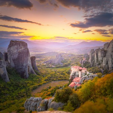 Yunanistan, Meteora 'nın panoramik manzarası. Gerçek güneş ve günbatımı gökyüzü ile romantik bir günbatımı zamanı. Meteora - inanılmaz kum taşı oluşumları. Meteora bölgesi UNESCO Dünya Mirası 'nda yer almaktadır. Yunanistan