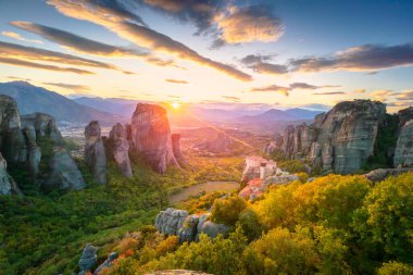 Meteora, Yunanistan. Yunanistan, Meteora 'nın panoramik manzarası. Gerçek güneş ve günbatımı gökyüzü ile romantik bir günbatımı zamanı. Meteora - inanılmaz kum taşı oluşumları. Meteora bölgesi UNESCO Dünya Mirası 'nda yer almaktadır. Yunanistan, Meteora