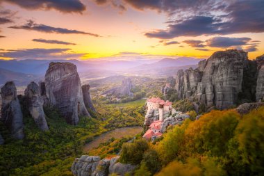 Yunanistan, Meteora 'nın panoramik manzarası. Gerçek güneş ve günbatımı gökyüzü ile romantik bir günbatımı zamanı. Meteora - inanılmaz kum taşı oluşumları. Meteora bölgesi UNESCO Dünya Mirası 'nda yer almaktadır. Yunanistan