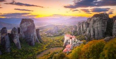 Yunanistan, Meteora 'nın panoramik manzarası. Gerçek güneş ve günbatımı gökyüzü ile romantik bir günbatımı zamanı. Meteora - inanılmaz kum taşı oluşumları. Meteora bölgesi UNESCO Dünya Mirası 'nda yer almaktadır. Yunanistan, Meteora