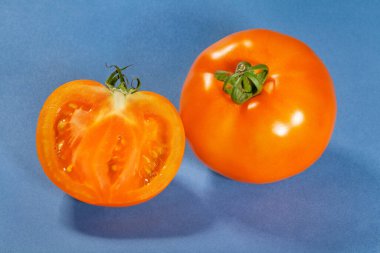Mavi arka planda dilimlenmiş portakal domatesi