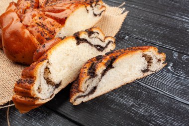 Tahta arka planda haşhaş tohumlu dilimlenmiş çörek.