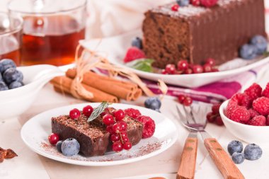 Chocolate sponge cake with fresh fruit on white dish.
