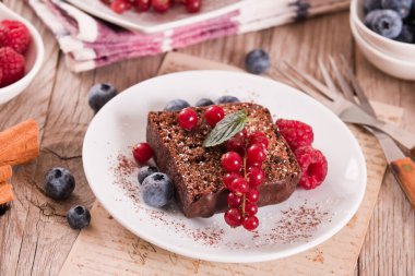 Chocolate sponge cake with fresh fruit on white dish.