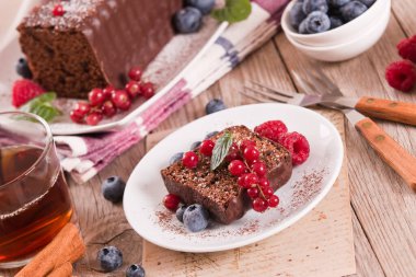 Chocolate sponge cake with fresh fruit on white dish.