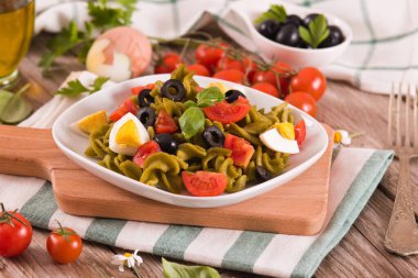 Fusilli pasta with cherry tomatoes, eggs and black olives.