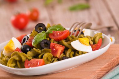 Fusilli pasta with cherry tomatoes, eggs and black olives.