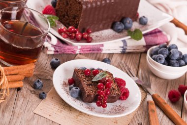 Chocolate sponge cake with fresh fruit on white dish.