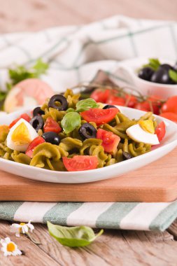Fusilli pasta with cherry tomatoes, eggs and black olives.