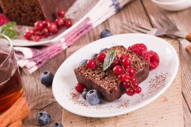 Chocolate sponge cake with fresh fruit on white dish.